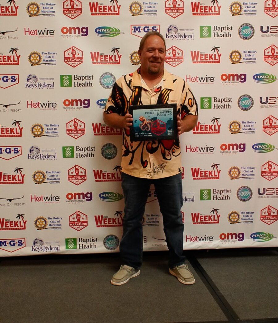 a man standing in front of a wall holding a plaque