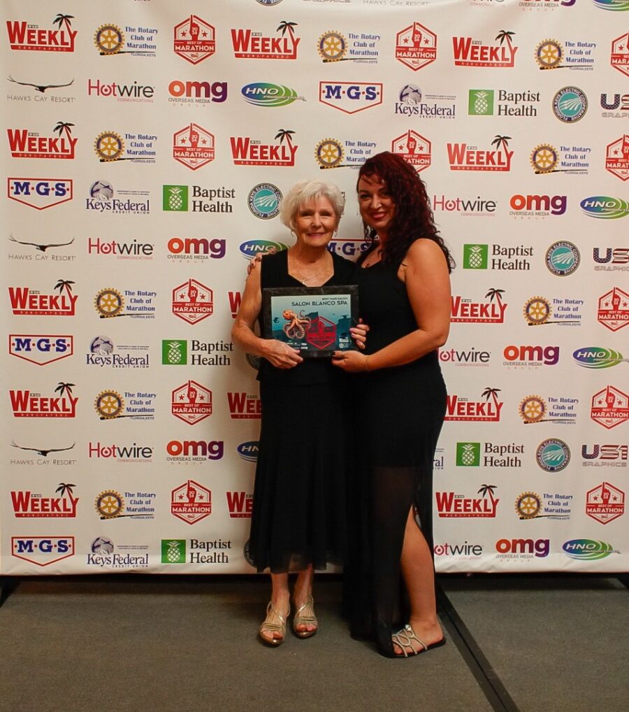 two women standing next to each other in front of a banner