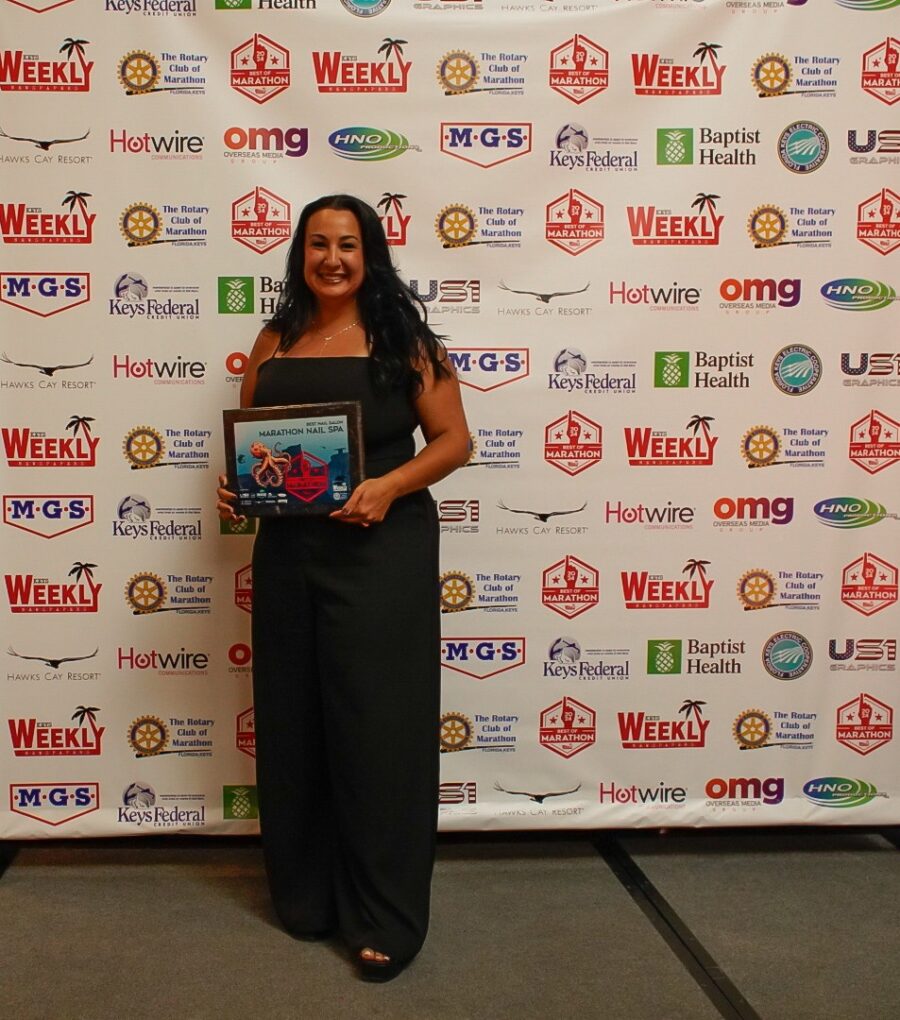 a woman standing in front of a wall holding a plaque