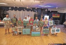 a group of people holding up paintings on a wooden floor