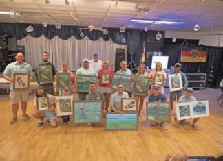 a group of people holding up paintings on a wooden floor