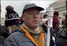 a man with a hat and scarf holding an american flag