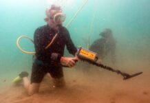 a man in a wet suit holding a scuba pole in the water