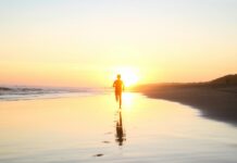 a person walking on the beach at sunset