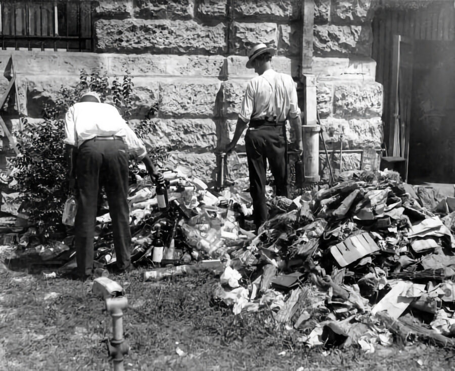 a couple of men standing next to a pile of trash