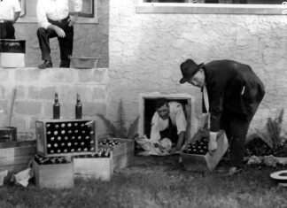 a black and white photo of a man opening a box