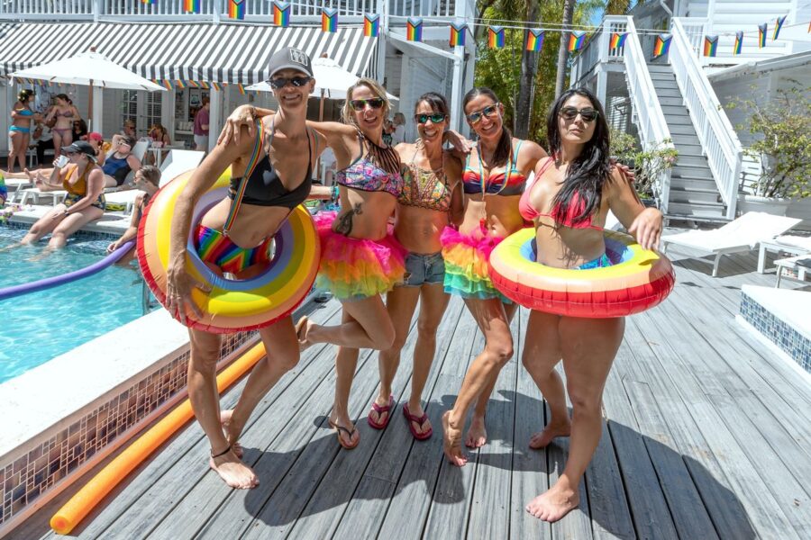 a group of women standing next to a swimming pool