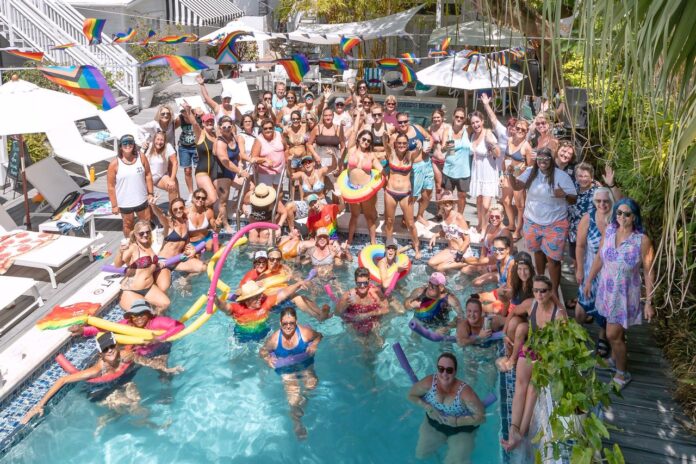 a group of people standing around a swimming pool