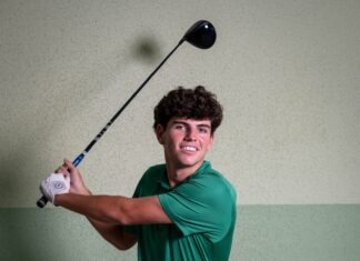 a man in a green shirt swinging a golf club