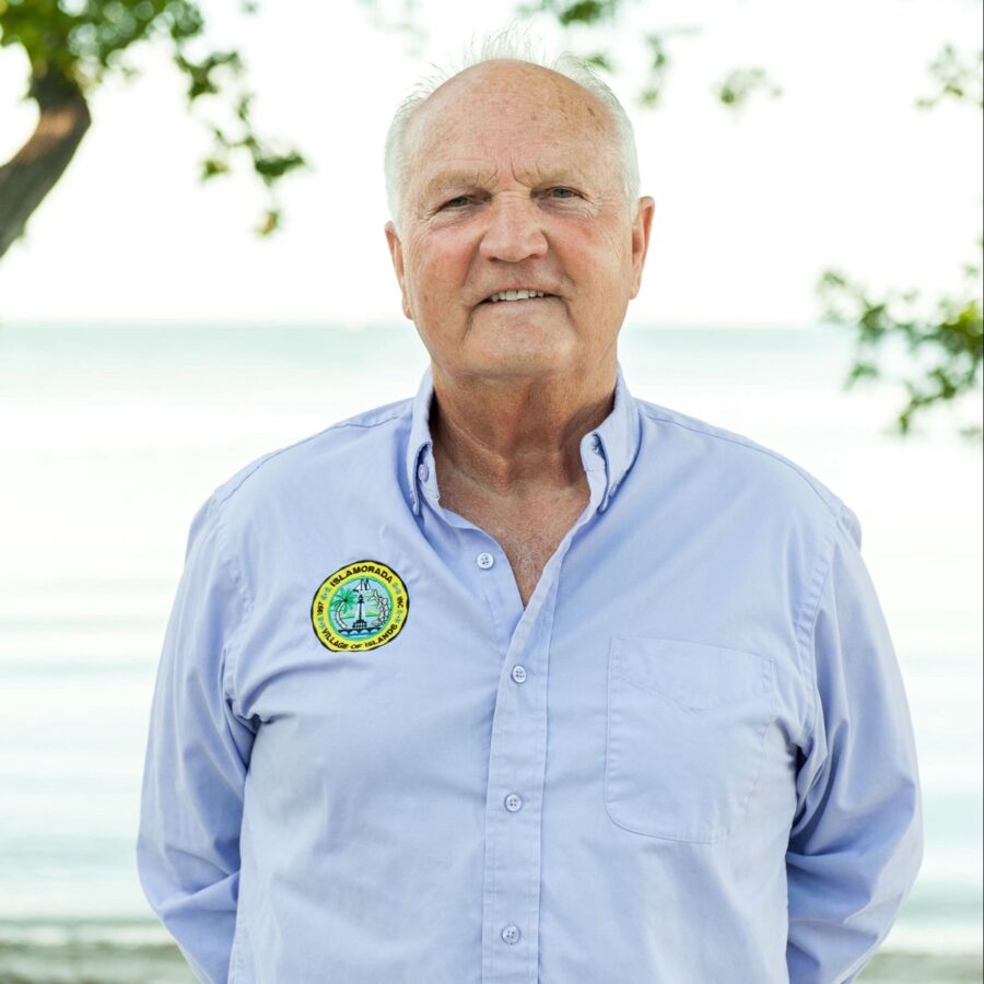 a man in a blue shirt standing in front of a tree