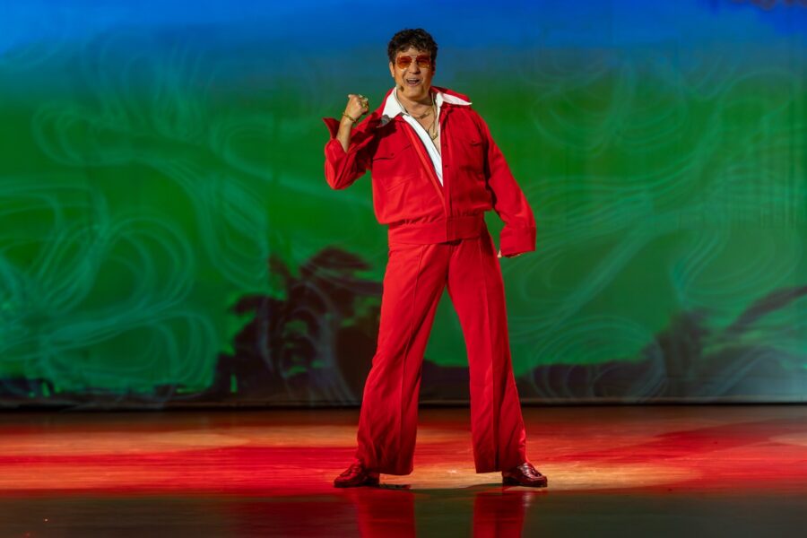 a man in a red suit standing on a stage