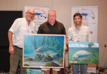 a group of people standing next to each other holding paintings