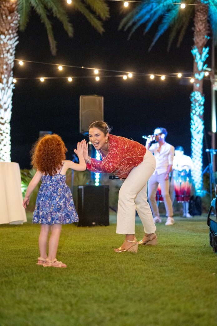 a woman and a little girl dancing in the grass