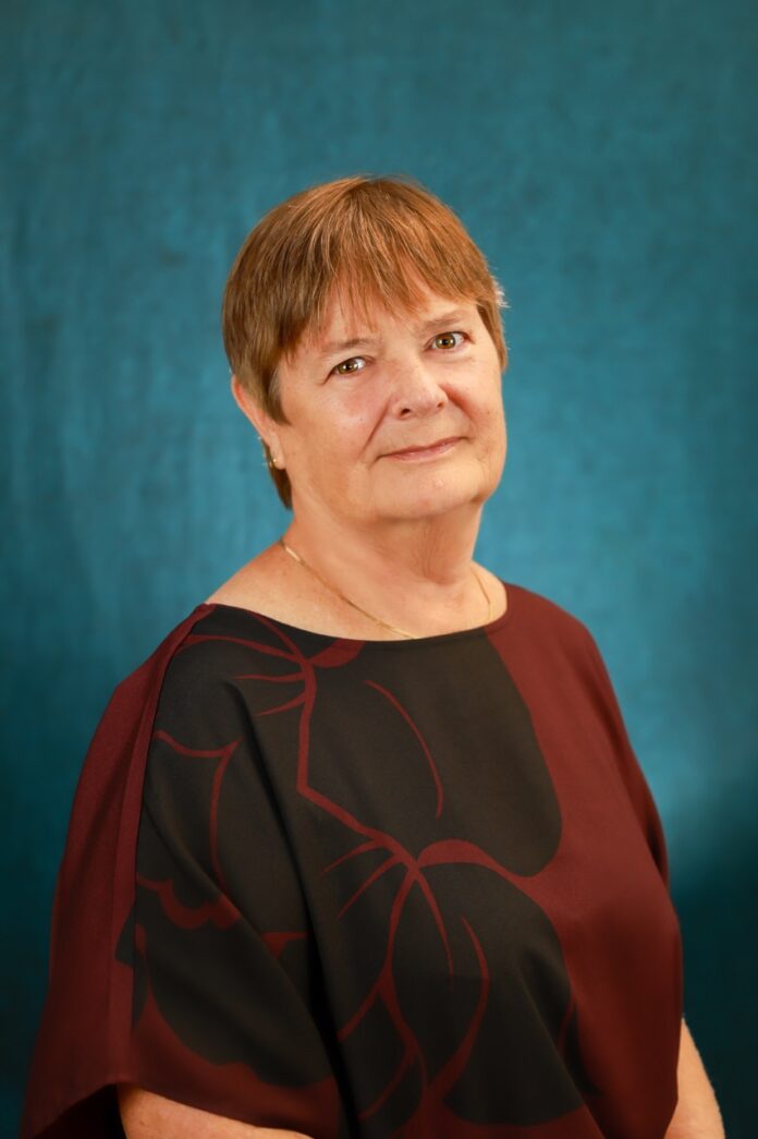 a woman in a black and red top standing in front of a blue wall