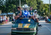 a group of people riding on the back of a green car