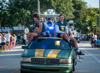 a group of people riding on the back of a green car