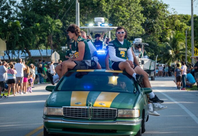 a group of people riding on the back of a green car