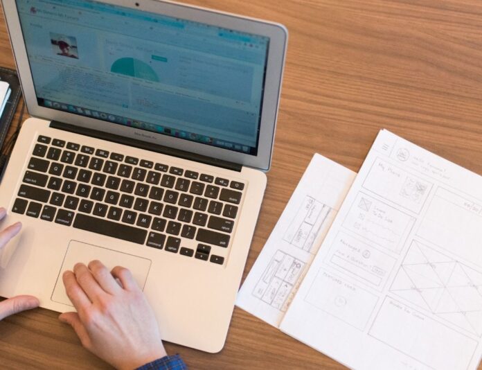 a person sitting at a table with a laptop and cell phone