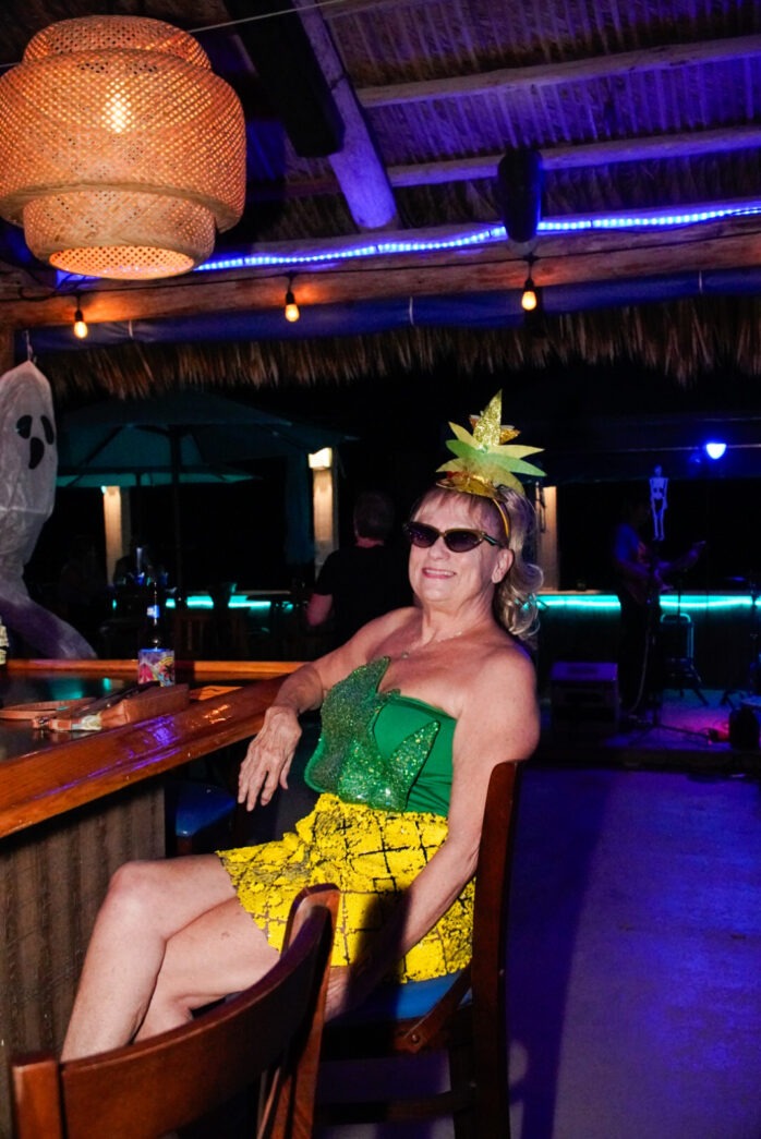 a woman sitting at a bar wearing a green dress