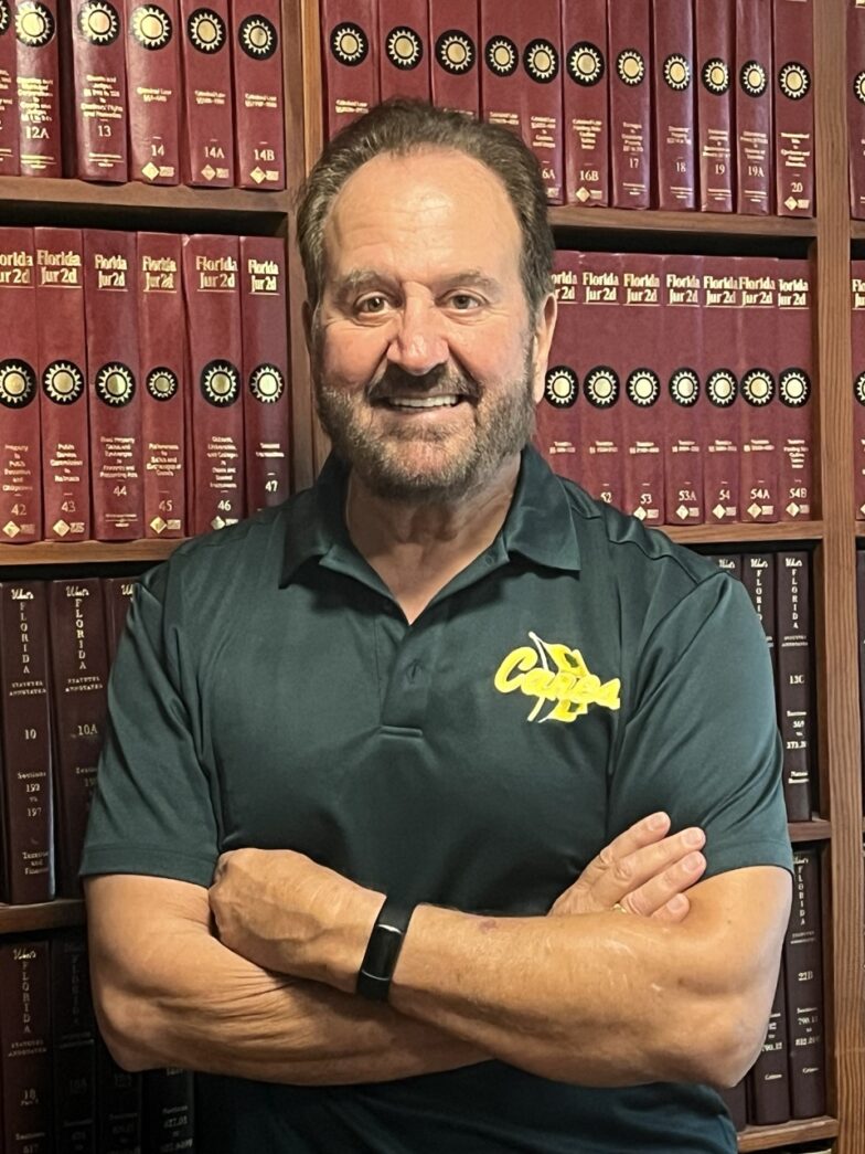 a man standing in front of a bookshelf with his arms crossed