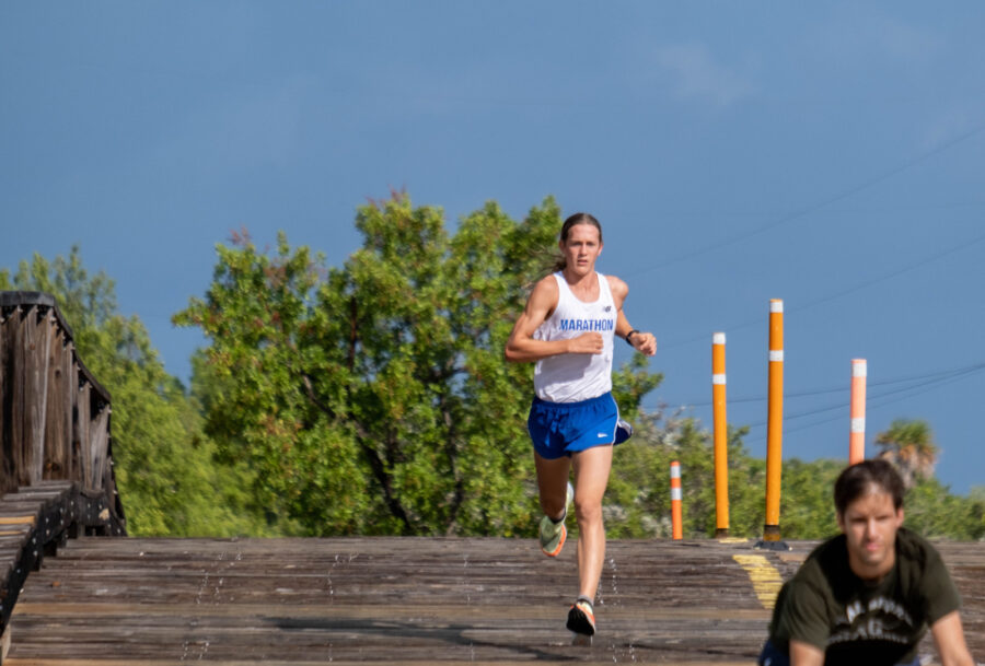 a man running across a wooden bridge over water