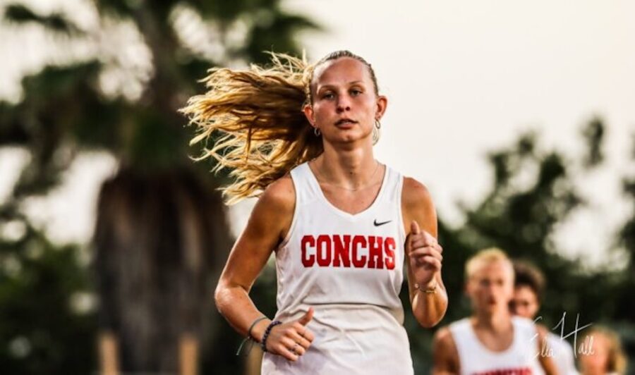 a woman running in a race with another woman behind her