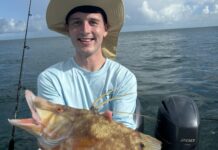 a man on a boat holding a large fish