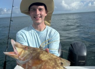 a man on a boat holding a large fish