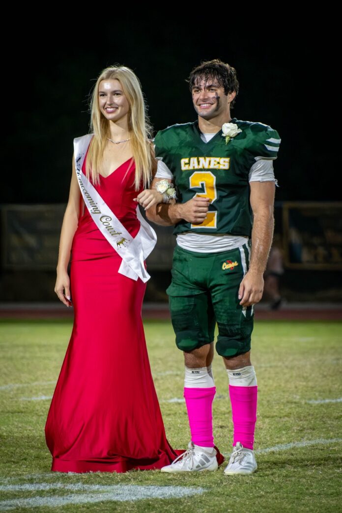 a woman in a red dress standing next to a man in a green uniform