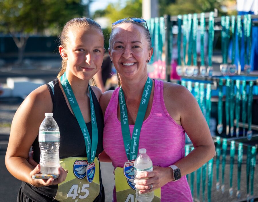 two women standing next to each other holding water bottles