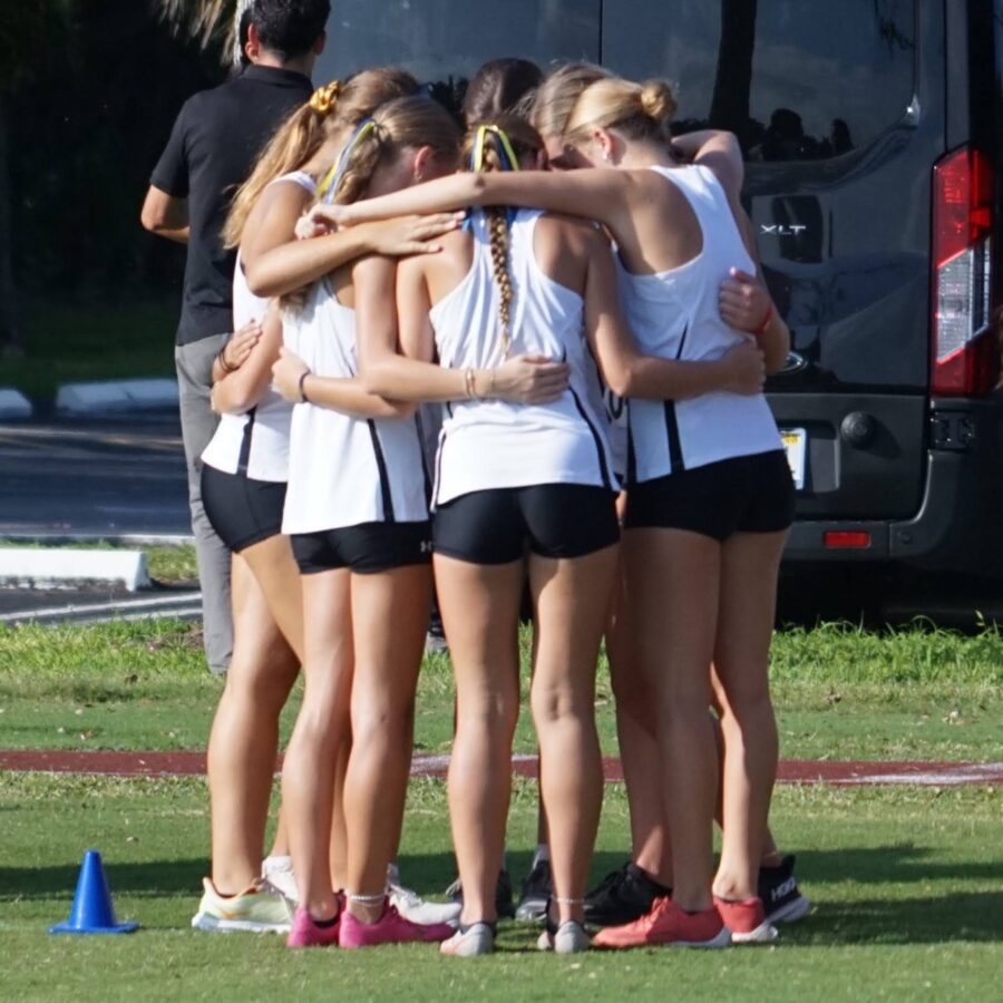 a group of girls huddle together in front of a bus