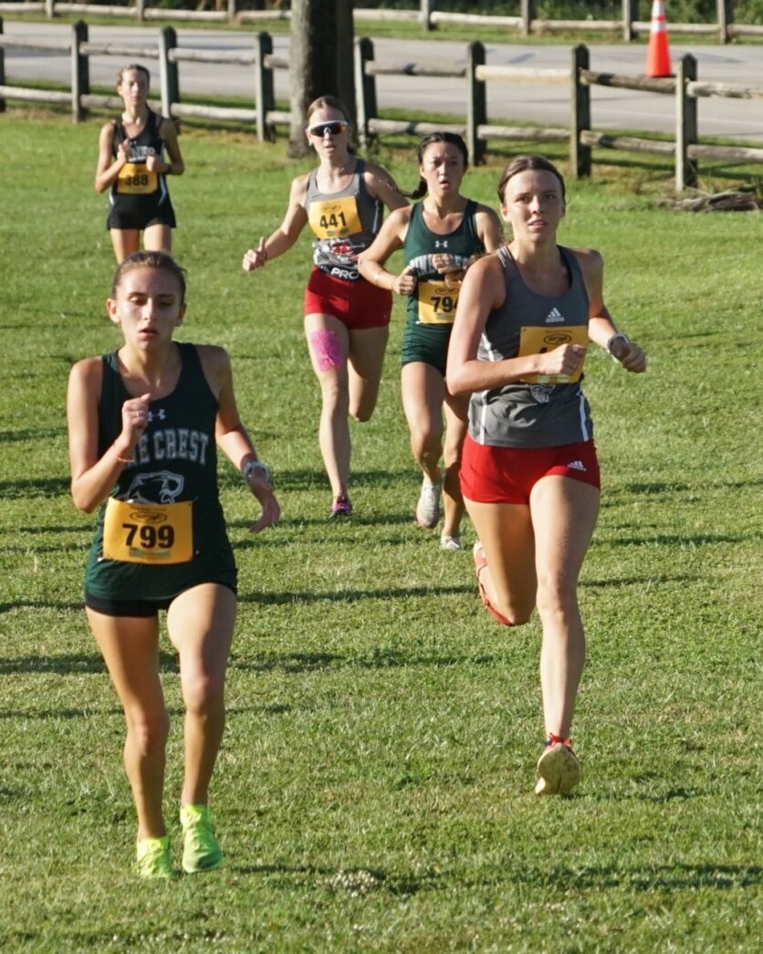 a group of women running across a lush green field