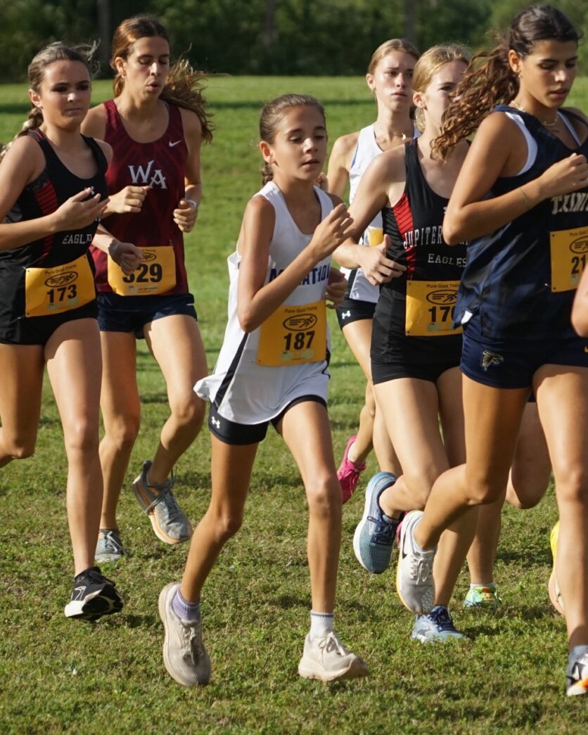 a group of girls running in a cross country race