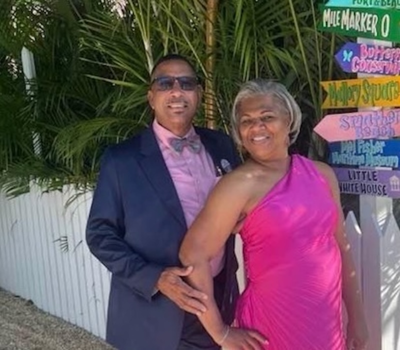 a man and a woman posing for a picture in front of a street sign