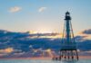 a lighthouse in the middle of the ocean at sunset