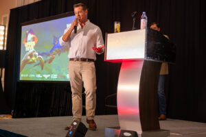 a man standing at a podium in front of a projector screen