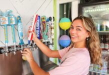 a woman is putting toothpaste on a toothbrush dispenser