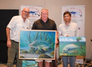 a group of people standing next to each other holding paintings