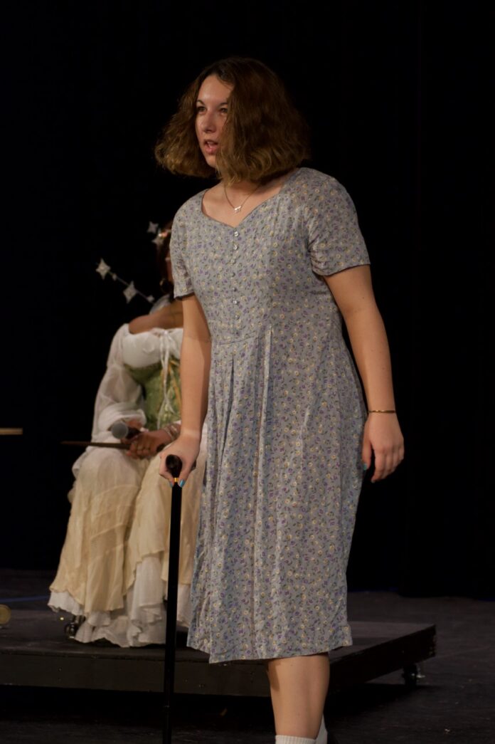 a woman standing on a stage with a cane