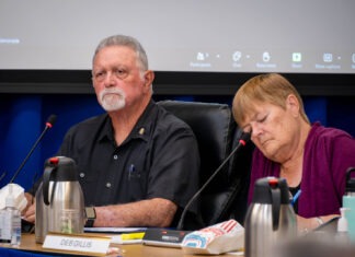 a man and woman sitting at a table in front of a projector screen