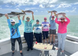 a group of people on a boat holding up fish