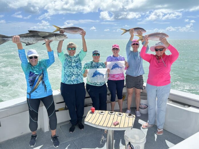 a group of people on a boat holding up fish