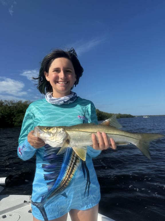 a woman holding a fish on a boat