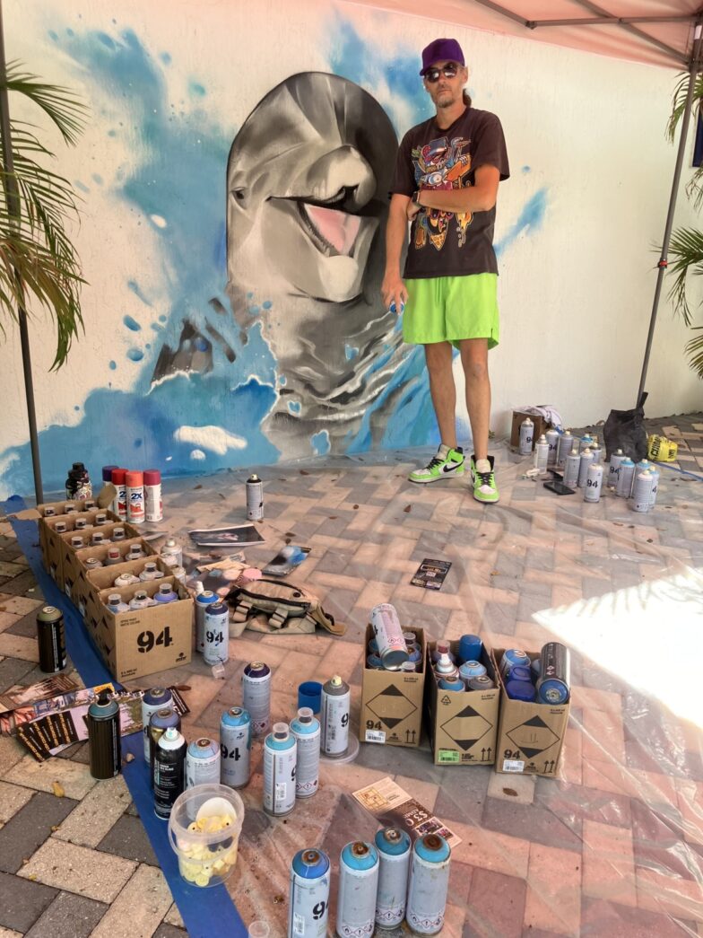 a man standing in front of a mural of a dolphin