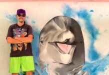 a man standing in front of a painting of a dolphin