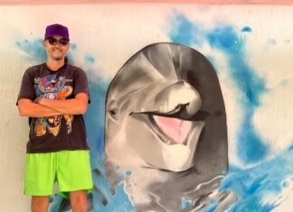 a man standing in front of a painting of a dolphin