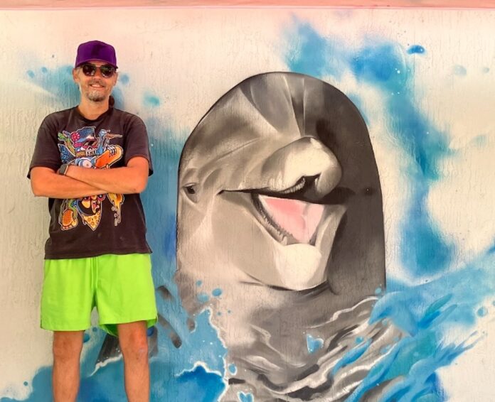 a man standing in front of a painting of a dolphin