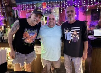 three men standing next to each other in front of a bar