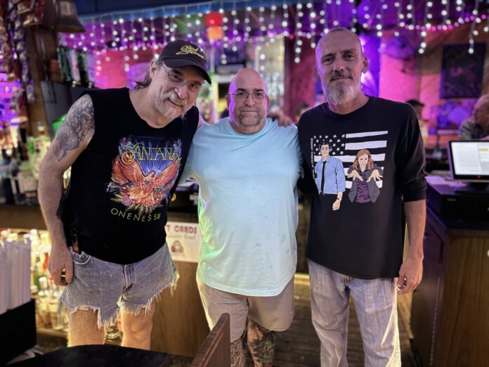 three men standing next to each other in front of a bar