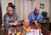 two men sitting on a couch holding a quilt